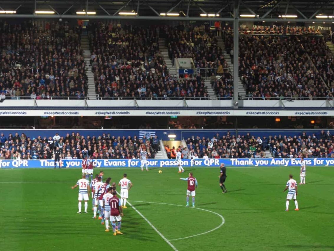 QPR and Aston Villa players lining up for a free kick at Loftus Road Stadium.