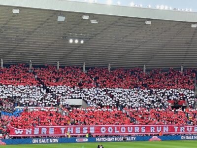 football fans holding up red and white placards in a display