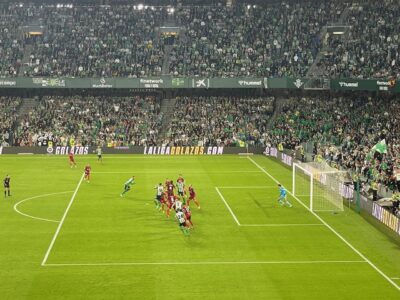 football players on the pitch for a corner kick in front of a full stadium.