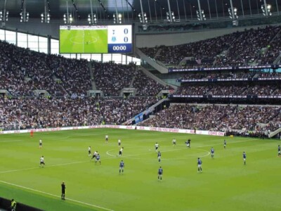 Players on the field in a full Tottenham Hotspur Stadium.