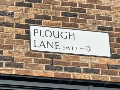 Back home again! sign reading Plough Lane, SW London