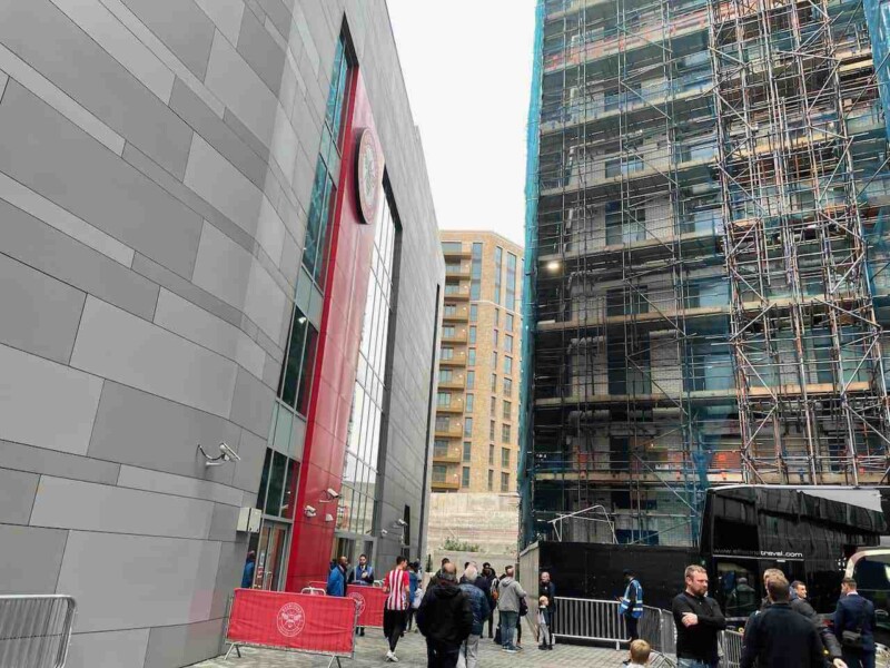 people outside brentford community stadium with apartment buildings nearby