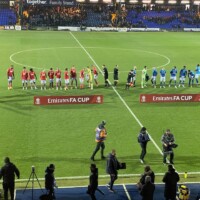 players lined up on a football pitch behind banners reading Emirates FA Cup