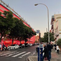 A football stadium on the left and apartments across the street on the right